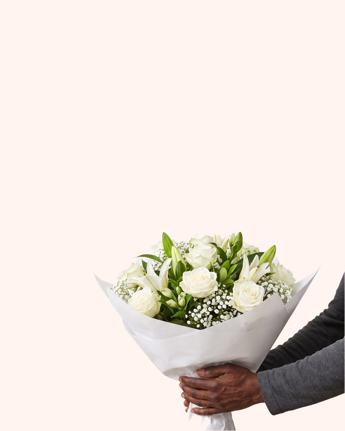 A pair of hands holding white roses and white lilies gently and carefully