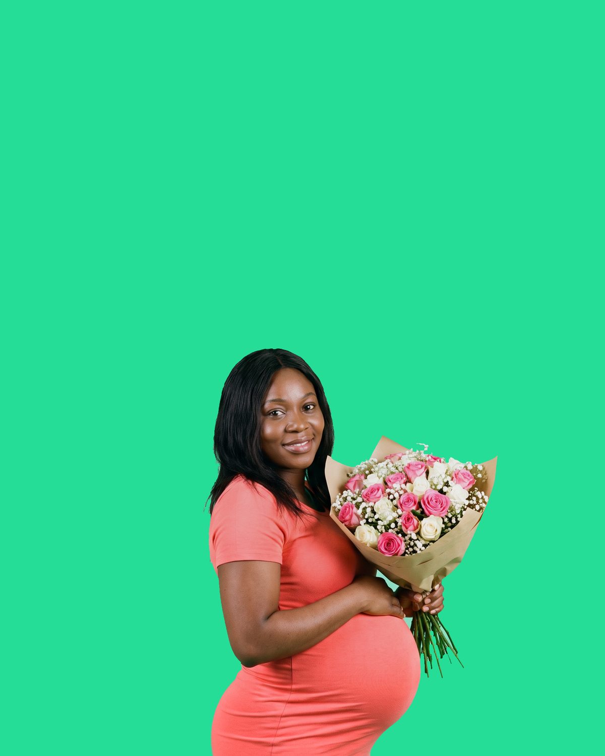 A pregnant woman in a coral dress, her bump clearly showing, holding a wrapped bouquet of pink roses and gypsophila