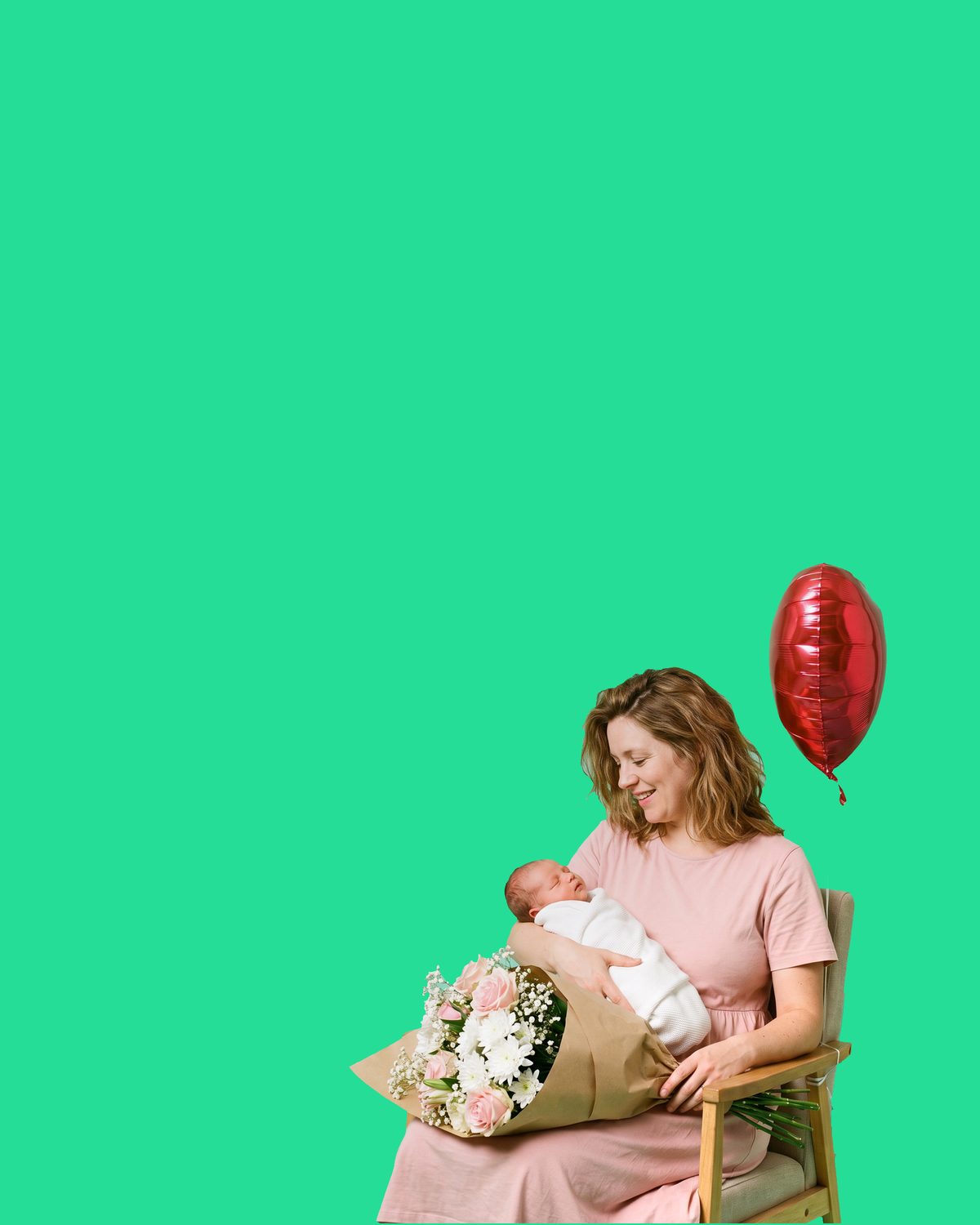 A seated woman in a pale pink dress smiling down at a newborn asleep in her arms, wrapped in a white blanket, a full kraft-wrapped bouquet of pink roses and white chrysanthemums across her lap and a red foil balloon tied to the back of her chair